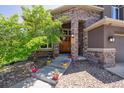 Inviting front entry with stone columns and colorful potted flowers lining the walkway at 14022 E Fair Pl, Centennial, CO 80111