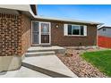 A welcoming entrance to the brick home with a concrete walkway and lush landscaping at 7350 Devinney Ct, Arvada, CO 80005