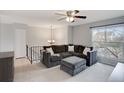 Bright living room with plush gray sectional sofa, ottoman, ceiling fan, and a large window at 11338 Donley Dr, Parker, CO 80138