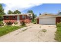 Red brick house with a detached garage and gravel driveway at 7475 W Vassar Ave, Lakewood, CO 80227