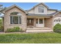 Inviting home entrance featuring a decorative front door, brick accents, flagstone steps, and manicured lawn at 6335 Oberon Rd, Arvada, CO 80004