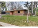 Home featuring a green garage door, wood paneling, and a well manicured lawn at 404 S Oneida Way, Denver, CO 80224