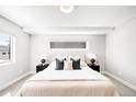 Bright bedroom features neutral walls, carpet flooring, stylish lamps, and black nightstands with modern decor at 3658 Quivas St, Denver, CO 80211
