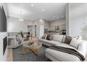 Open living room showcasing a sectional sofa, coffee table, and views into the kitchen at 3893 Freestone Pt, Castle Rock, CO 80108
