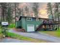 Charming two-story green home with a deck and garage surrounded by trees with a camper and stone at 5237 S Olive Rd, Evergreen, CO 80439
