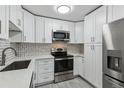 Modern kitchen featuring stainless steel appliances, mosaic backsplash, and sleek white cabinetry at 695 S Alton Way # 5A, Denver, CO 80247