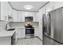 Bright kitchen with stainless steel appliances, mosaic tile backsplash, white cabinets, and modern lighting at 695 S Alton Way # 5A, Denver, CO 80247