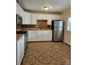 Updated kitchen featuring white cabinets, stainless steel appliances, and eye-catching patterned tile floors at 1390 Ash Ct, Thornton, CO 80229