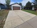 A long concrete driveway leads up to an attached garage on this suburban home at 3735 S Lewiston St, Aurora, CO 80013