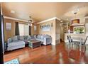 Cozy living room featuring hardwood floors, a large sectional, and an open layout to dining area at 12770 Jasmine Ct, Thornton, CO 80602