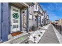 Townhome entrance with gray siding, white door, and snowy walkway at 9275 Merino Ct # A, Littleton, CO 80125