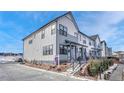 Modern townhome with gray and white exterior, landscaped yard, and black metal fence. Additional homes are visible at 9275 Merino Ct # A, Littleton, CO 80125