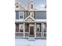 Two-story townhome with gray siding, brick accents, and a front porch at 14721 E Poundstone Dr, Aurora, CO 80015