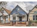 Charming blue and white two-story home with peaked roof and inviting front porch behind black iron fence at 160 W Bayaud Ave, Denver, CO 80223