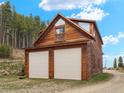 Charming exterior of a two-story home with a two-car garage and beautifully wooded surroundings at 197 Sawmill Ln, Idaho Springs, CO 80452