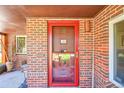 Close-up of a classic brick home featuring a striking red front door and brickwork at 2901 Monaco Pkwy, Denver, CO 80207