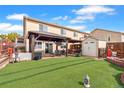 Spacious backyard featuring a covered patio, artificial turf, wooden fence, and storage shed at 8240 Clayton Ct, Denver, CO 80229