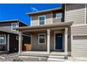 Inviting front porch with white pillars, a blue front door, and a cozy, covered entryway at 2325 Mountain Sky Dr, Fort Lupton, CO 80621