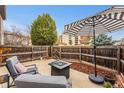 Private backyard patio with comfortable seating, umbrella, and a fire pit at 7250 Eastmoor Dr # 119, Denver, CO 80237
