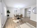 Cozy dining room featuring a modern chandelier and wood-look flooring adjacent to kitchen at 2032 Tulane St, Denver, CO 80260