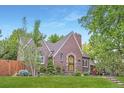 A brick home featuring a beautiful roof line, mature landscaping, and a lush green lawn at 926 S Fillmore Way, Denver, CO 80209