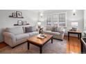 Bright living room featuring neutral-toned sofas, hardwood floors, plantation shutters, and decorative shelves at 926 S Fillmore Way, Denver, CO 80209