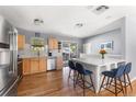 Open-concept kitchen featuring stainless steel appliances, white island with seating, and hardwood floors at 10640 Nw Routt Way, Westminster, CO 80021