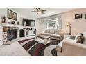 Cozy living room features a fireplace, ceiling fan, stylish rug, and comfortable seating at 25128 E Maple Ave, Aurora, CO 80018