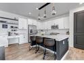 Modern kitchen featuring a large island with seating, white cabinets, stainless steel appliances, and stylish lighting at 2089 S Fultondale Way, Aurora, CO 80018