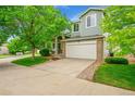 Inviting two-story home featuring a manicured lawn, a two car garage, and mature trees at 10571 Garfield St, Thornton, CO 80233