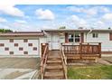 Inviting home with a wooden porch, attached garage, and a neatly manicured front lawn at 6327 Fenton St, Arvada, CO 80003