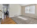 Carpeted living room with adjacent hardwood flooring, light walls, and a large bright window at 10517 Madison St, Thornton, CO 80233