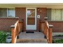 Close-up of the brick facade and entrance with wood railing at 3182 W Radcliff Dr, Englewood, CO 80110