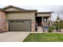 Home exterior with a two-car garage, stone accents, and inviting front porch and well-manicured lawn at 7029 Sagerock St, Castle Pines, CO 80108
