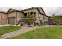 A beautiful house with lush green grass, stone accents, a welcoming entryway, and well-maintained landscaping at 7029 Sagerock St, Castle Pines, CO 80108