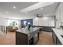 Open concept kitchen and living room with a large island, hardwood floors, and abundant lighting at 6742 Cole Cir, Arvada, CO 80004