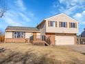 Charming split-level home featuring tan siding, brick accents, and a two-car garage at 11535 Albion Ct, Thornton, CO 80233