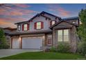 Charming two-story home featuring a stone facade, three-car garage, and striking red shutters at 24556 E Ottawa Ave, Aurora, CO 80016