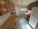 Kitchen with wood cabinets, tile flooring, laminate counters, and white appliances in a home that needs some TLC at 7810 Pontiac St, Commerce City, CO 80022