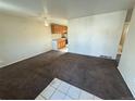 Neutral living room featuring brown carpet, ceiling fan, and tile accent, leading into the kitchen in this home at 7810 Pontiac St, Commerce City, CO 80022