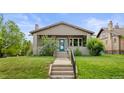 Inviting bungalow with a well-manicured lawn, covered porch, and a cheerful blue front door at 2703 N Milwaukee St, Denver, CO 80205