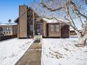 A charming one-story home with wood siding and stone accents, situated on a snow-covered lot at 245 Cedar St, Hudson, CO 80642