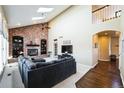Spacious living room with a vaulted ceiling, brick fireplace, and a staircase overlooking a large sectional sofa at 15407 E Crestline Pl, Centennial, CO 80015