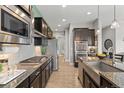 Modern kitchen featuring stainless steel appliances, dark cabinetry, granite countertops, and a stylish island at 17358 W 95Th Ave, Arvada, CO 80007