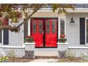 Close-up of a vibrant red front door with decorative glass, framed by brick columns and fresh flowers at 5440 W Hinsdale Ave, Littleton, CO 80128