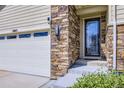 Close-up of the front door and garage showcasing the stone and siding details at 6863 E 132Nd Pl, Thornton, CO 80602
