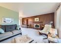 Spacious living room featuring wood paneling, a brick fireplace, comfortable seating, and neutral carpet at 4257 Graham Ct, Boulder, CO 80305