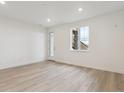 Bright, white-walled living room with light wood floors and a door to the outside at 8229 Butte Creek St, Littleton, CO 80125