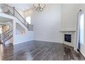 Bright, open-plan living room with a fireplace, wooden floors, and a staircase to the upper level at 2474 Ravenswood Ct, Longmont, CO 80504