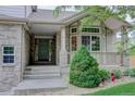 Inviting front porch featuring a bay window, brick pillars, and verdant landscaping at 14910 Williams St, Thornton, CO 80602